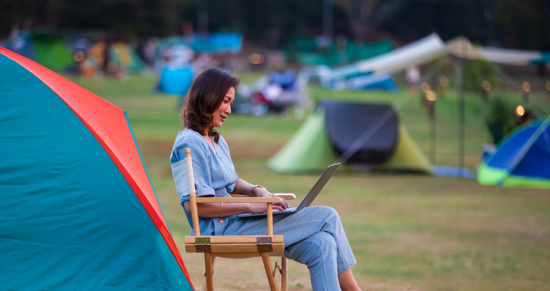 Woman working on laptop at campsite, highlighting campground wifi solutions and wireless internet solutions for business